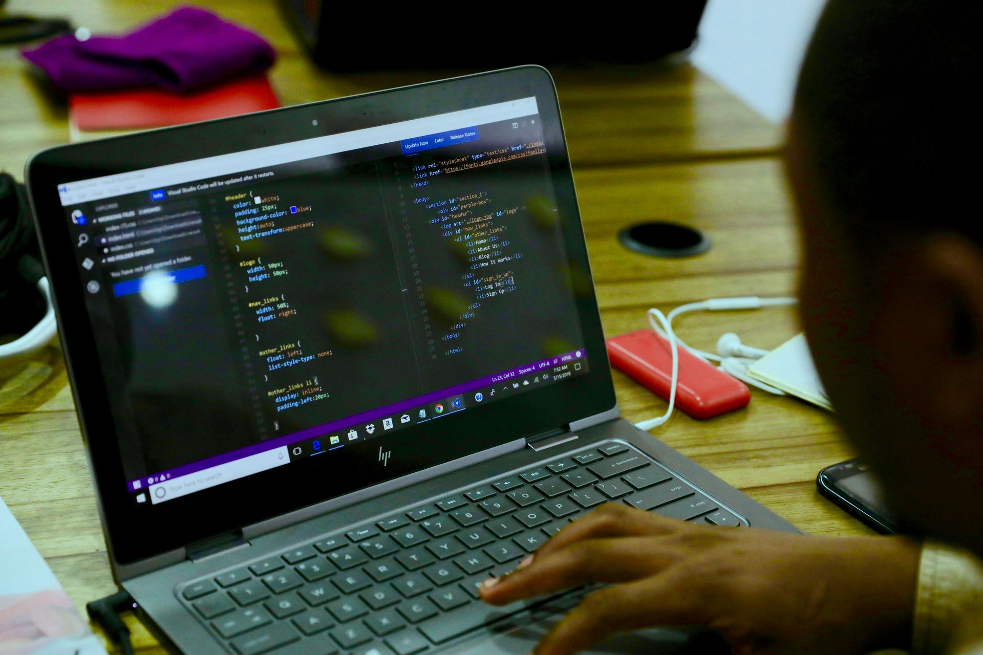Child writing real HTML and CSS code in Visual Studio Code on a laptop