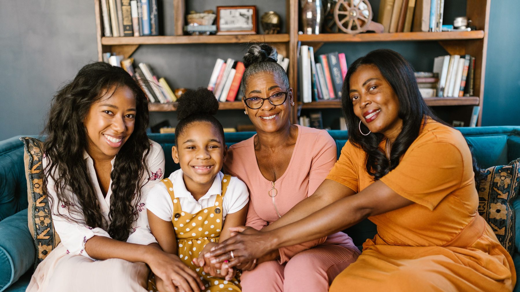 Three generations of a family sitting together on a sofa, representing the bond of speaking Yoruba with grandmother